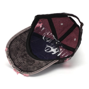 Detailed view of internal lining and pink distressed edges on a washed denim cap