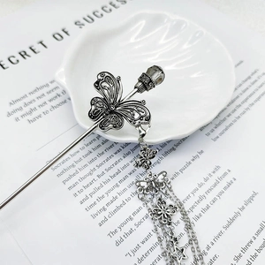 Pic à cheveux papillon en argent antique avec pompons et perles sur un plateau