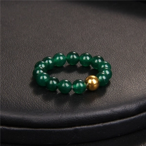 Macro shot of minimalist beaded ring with green natural stone beads and gold metal accent