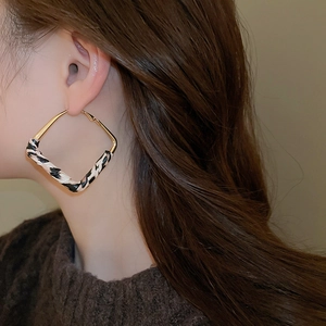 Detailed view of square gold earring with leopard print wrap on a female model