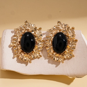 Close-up of vintage oval black stone earrings with gold leaf-textured metal base