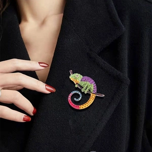 Detailed close-up of a vintage lizard brooch with colorful crystals on a black coat lapel