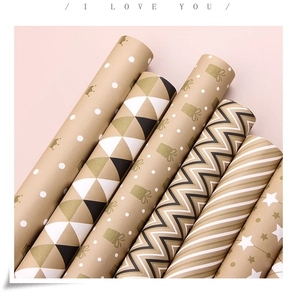 Detail of kraft gift wrapping paper rolls with gold and black geometric patterns