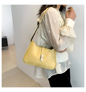 Side view of model wearing a yellow suede shoulder bag with black strap and metal buckle