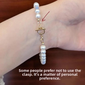 Detail view of pearl bracelet with blue bead and golden toggle clasp on wooden table