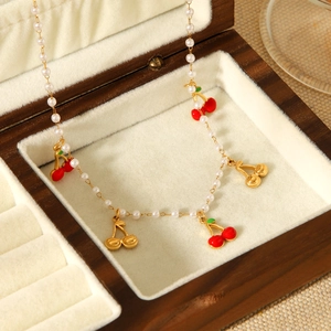Collier cerise doré avec perles et émail rouge dans un écrin à bijoux en bois