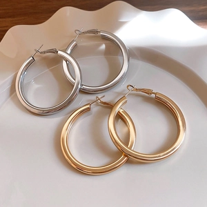 Close-up of gold and silver hoop earrings on a white ceramic plate with a glossy finish