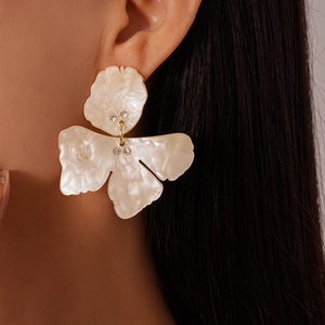 Close-up of pearl white floral drop earrings with rhinestones on a female model