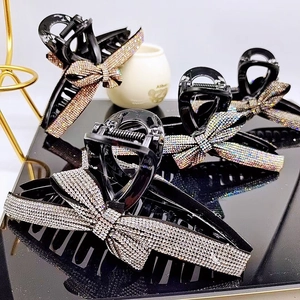 Detail of four sparkling rhinestone bow hair claws in silver, rainbow, purple, and gold