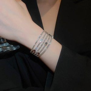 Close-up of layered silver bracelet with pavé diamonds and shiny sequins on a model