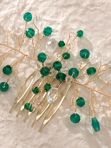 Macro detail of handmade bridal hair comb with gold leaves and emerald green crystals