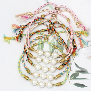 Macro shot of colorful braided rope bracelets with glass pearls and golden beads accents