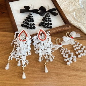 Detailed macro view of bowknot pearl earrings featuring lace tassels and rhinestone accents