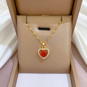 Close-up of heart-shaped red gemstone necklace with diamond halo in a jewelry box