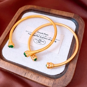 Macro shot of vintage gold bangles with emerald and ruby gemstones on a white cloth