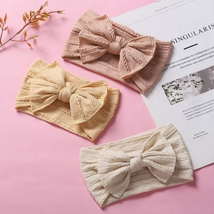 Three nylon baby bow headbands with jacquard knit texture in beige and soft pink colors