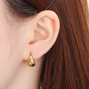 Close-up of gold U-shaped stainless steel hoop earring with three star-set zircons