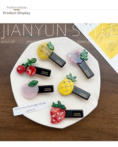 Detailed macro of acrylic fruit hair clips with rhinestones and handmade gold lettering