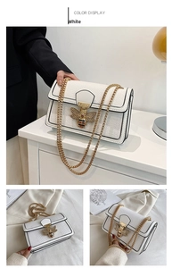 Detail of white faux snake pattern crossbody bag with gold bee buckle and chain