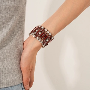 Dettaglio di un bracciale elastico vintage bronzo con resina rossa e strass bianchi