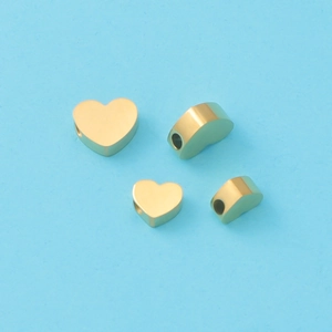 Détail de quatre perles d'espacement en forme de cœur dorées pour la création de bijoux