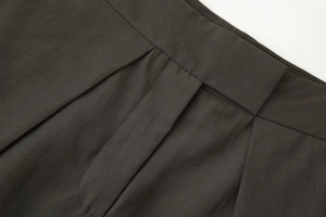 Détail du tissu en sergé gris foncé et de la taille plissée d'un pantalon large