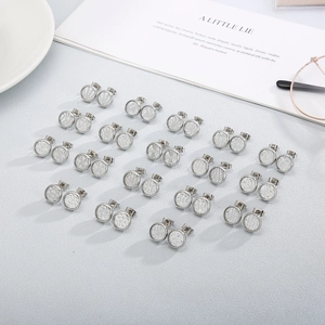 Set of round stainless steel stud earrings with textured geometric patterns on grey desk