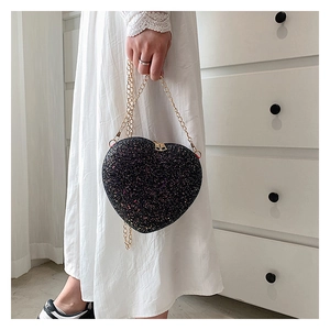 Detail of a heart-shaped glitter shoulder bag with golden chain and sequin texture
