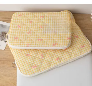 Detailed close-up of yellow gingham quilted laptop and tablet sleeve with pink bow embroidery