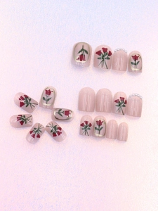 Macro detail of tulip press-on nails featuring red floral art and white micro pearls