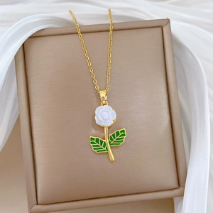 Luxurious gold titanium necklace with white flower pendant on a beige jewelry box
