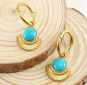 Detailed shot of 18K gold fan earrings with blue turquoise on a rustic wood background
