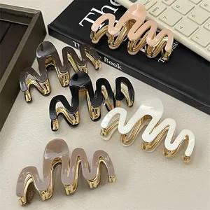 Close-up of wavy metal and acetate hair claws in various Morandi colors on a desk
