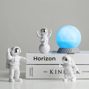 Detailed view of three resin astronaut figurines with a glowing blue moon lamp
