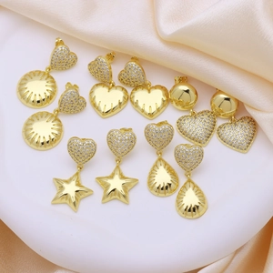 Elegant gold earrings set with heart star and teardrop charms on champagne satin