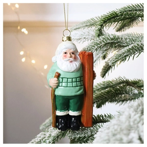 Close-up of a Santa Claus ornament in mint green hanging on a snowy Christmas tree branch