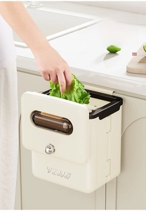 Detail view of a cream wall-mounted kitchen bin with trash bag storage and silver handle