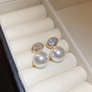 Macro shot of gold-plated pearl earrings with sparkling cubic zirconia on soft velvet