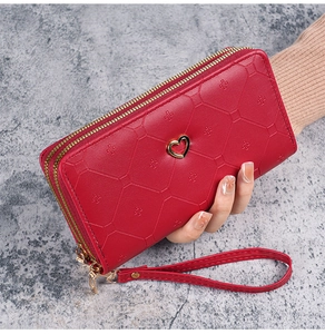 Close-up of red long wallet with quilted pattern, double zippers and heart ornament
