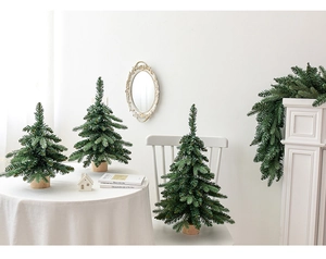 Three mini artificial Christmas trees with wooden bases and green pine garland decor