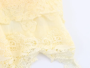 Détail de tissu en dentelle jaune clair avec broderie florale délicate et texture en maille
