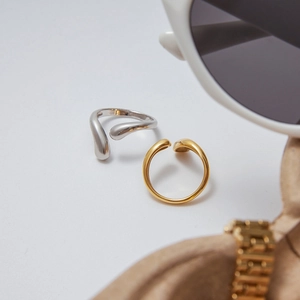 Minimalist teardrop open rings in gold and silver finish on a stylish wooden tray