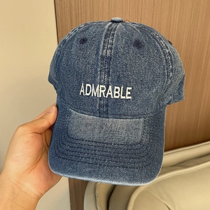 Close-up of ADMRABLE embroidery on vintage washed denim baseball cap with twill texture