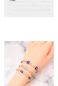 Detail view of gold-plated titanium chain bracelet set featuring evil eye and star charms