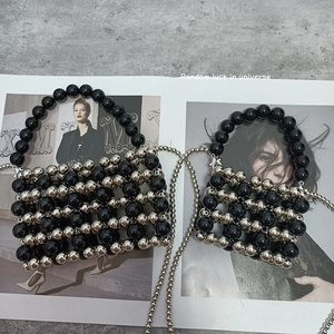 Flat lay of small and large silver beaded handbags with metal chain straps on magazines
