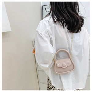 Mini macaron jelly bag in apricot with gold chain strap worn as a stylish crossbody bag