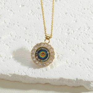 Macro shot of gold evil eye pendant with sparkling zircons on white stone surface