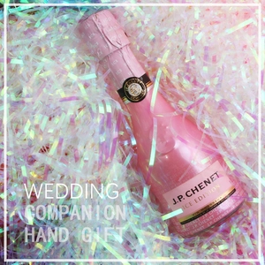 Iridescent shredded raffia paper filler surrounding a mini pink sparkling wine bottle