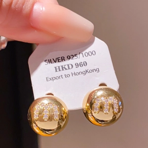 Close-up of gold plated 925 silver stud earrings with m-shaped crystals and bow pearl detail