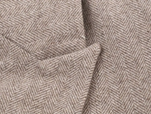 Detailed close-up of brown herringbone wool fabric texture on the blazer lapel